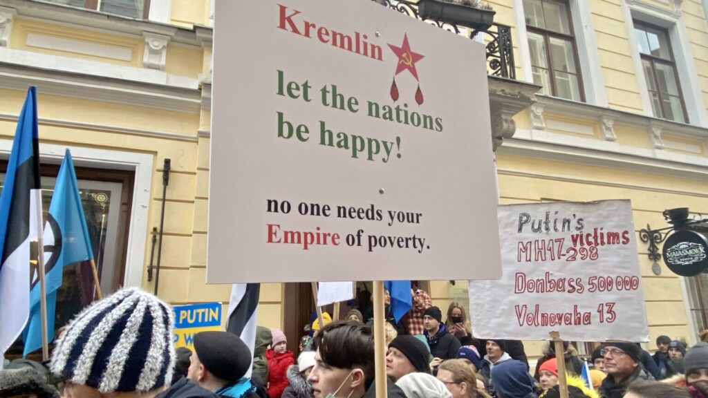 Protesters in Estonia hold signs criticizing Russian aggression and the Kremlin, reflecting national frustration over foreign policy and regional security concerns.