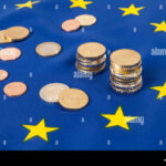 Euro coins on the EU flag highlight financial operations under the European economic system.