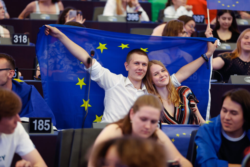 Young Europeans show their support for a stronger EU by waving the flag in the European Parliament, reflecting a growing youth movement for deeper integration.