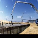 Heavy machinery and workers pour concrete at a major power plant construction site, symbolizing Europe's investment in energy infrastructure.