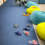 A cozy, colorful lounge area in a hospice facility, with slippers arranged neatly on the floor and bean bags providing comfort for patients.