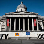 A historic government building is framed by protest banners, symbolizing public dissent or political messaging.