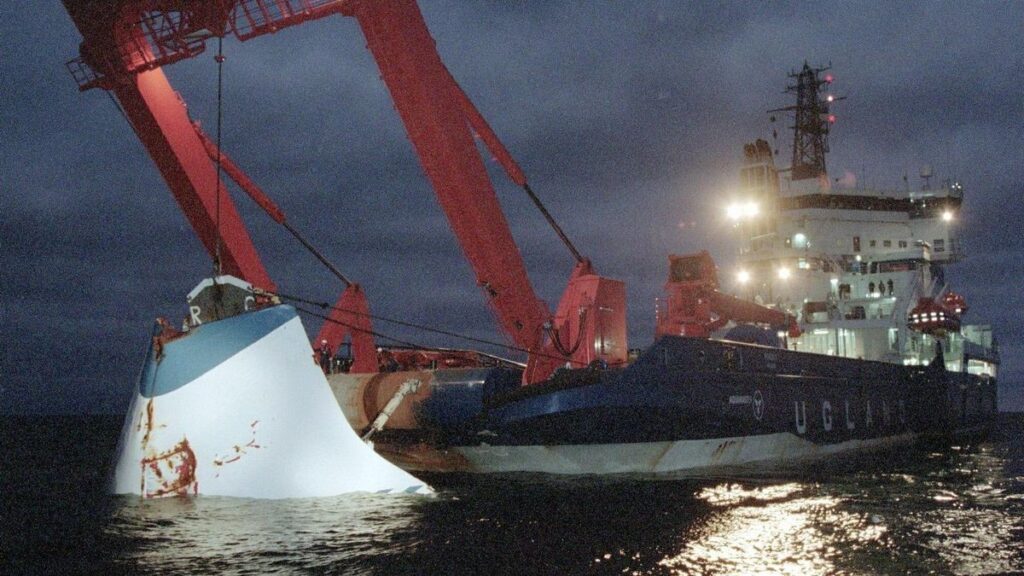 A damaged vessel, the 'Uglad', is being lifted by a crane at night, highlighting a maritime incident that may be linked to the shadowy operation involving beetles and candy shipments that allegedly aided Russian troops.